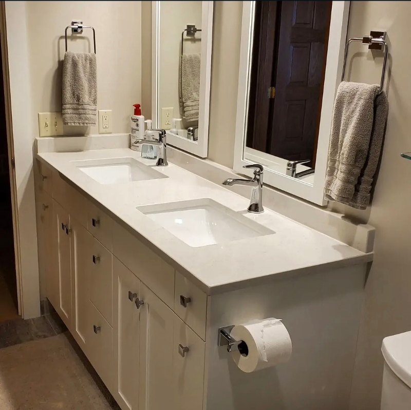 Bathroom vanity with two undermount sinks in a white counter, mirrored walls, and pendant lights