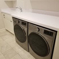 White laundry-room built-ins with drawers, hanging space, and cubbies for shoes under a sloped ceiling